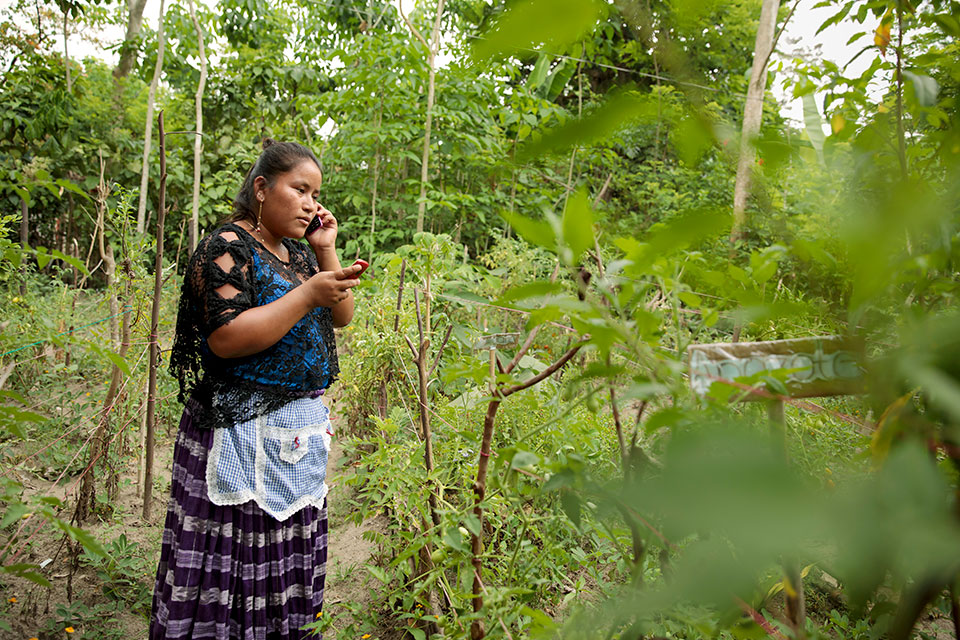 A woman speaks on her cell phone in a field in Guatemala. Photo: UN Women/Ryan Brown