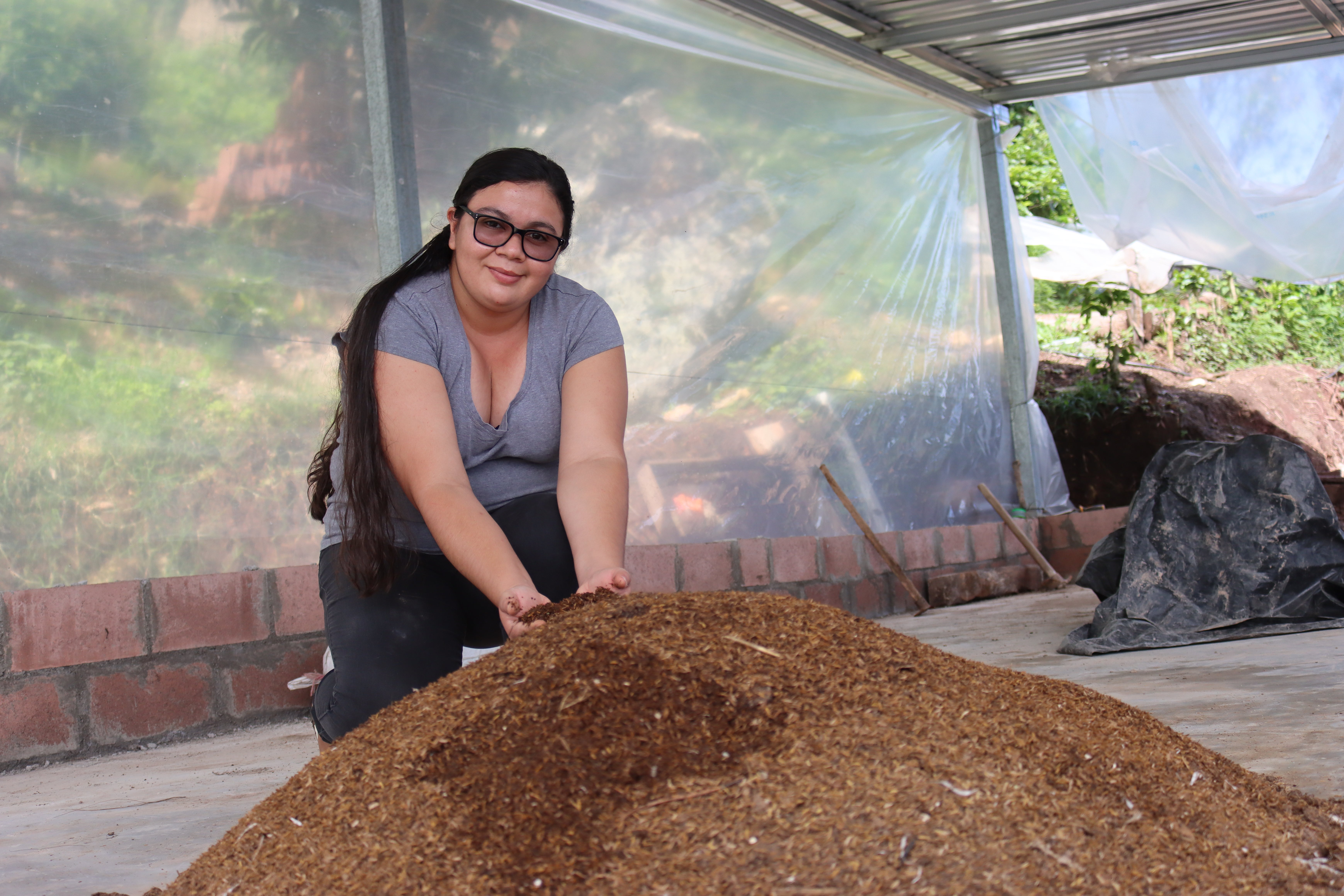 Karla Escobar junto al abono orgánico en la planta de producción de ECOFUT, construida gracias al premio ganado del proyecto ESCALAR Juventud 2024 del CATIE.