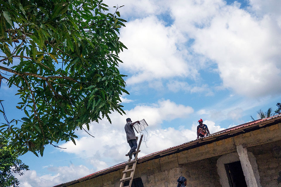In Liberia, solar engineers install a solar panel on the roof of a village house, bringing electricity to this home for the first time. Photo: Thomas Dworzak/Magnum Photos for UN Women