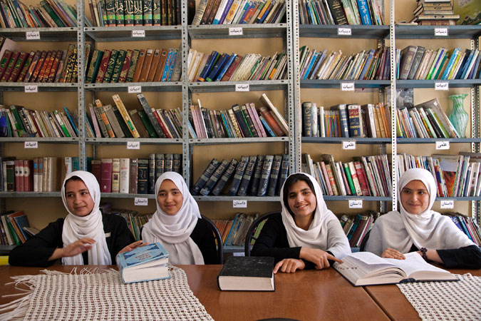 Four young women in front of bookcase in Afghanistan. Photo: World Bank/Graham Crouch