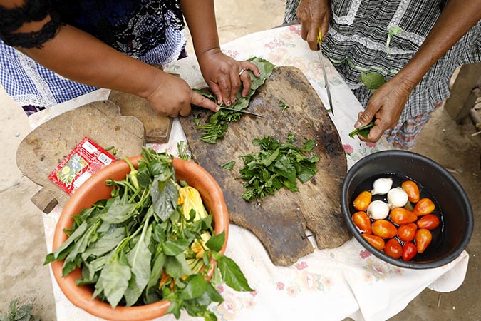 Women chop vegetables and lettuce. Photo: UN Women/Ryan Brown