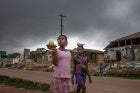 Girls in the town of Totota in Bong County walk past homes that are being demolished as the government rebuilds roadways. Photo: Thomas Dworzak/Magnum Photos for UN Women